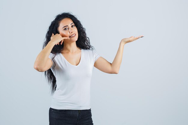 Young brunette woman showing phone gesture