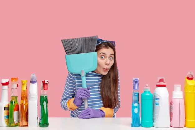 Young brunette woman sitting next to cleaning products