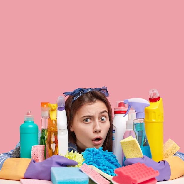 Free photo young brunette woman sitting next to cleaning products