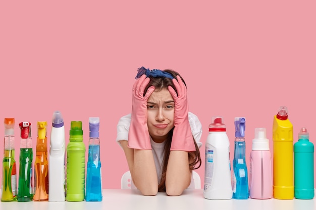 Young brunette woman sitting next to cleaning products