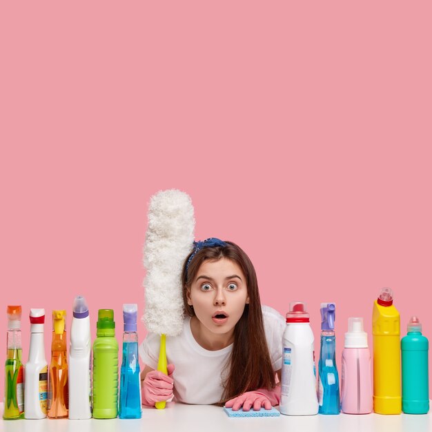 Young brunette woman sitting next to cleaning products