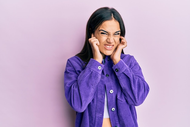 Free photo young brunette woman wearing casual clothes covering ears with fingers with annoyed expression for the noise of loud music deaf concept