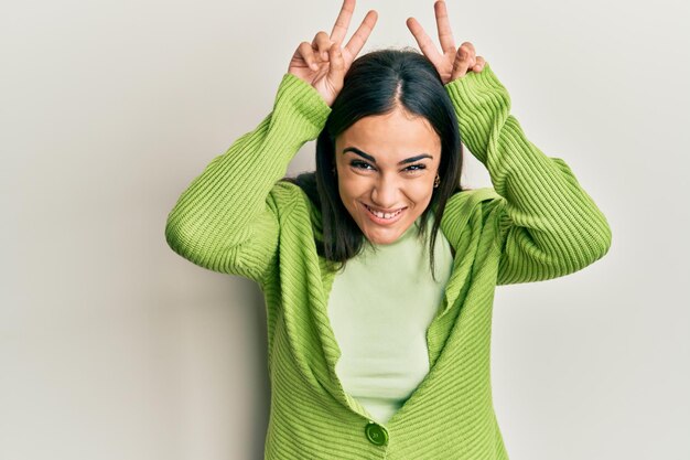 Young brunette woman wearing casual clothes posing funny and crazy with fingers on head as bunny ears smiling cheerful