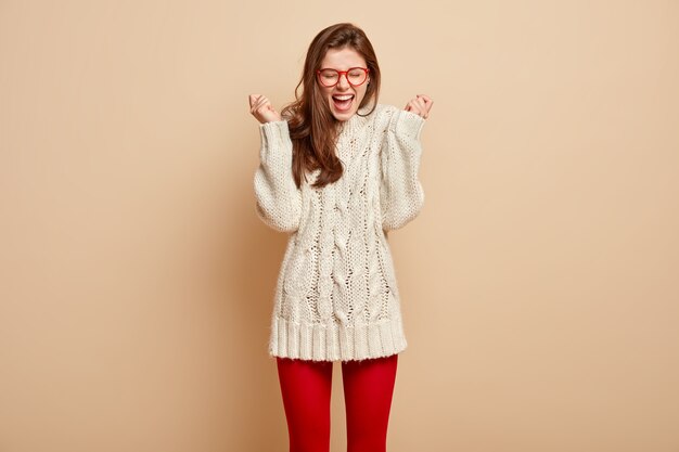 빨간 안경과 흰색 스웨터를 입고 젊은 갈색 머리 여자