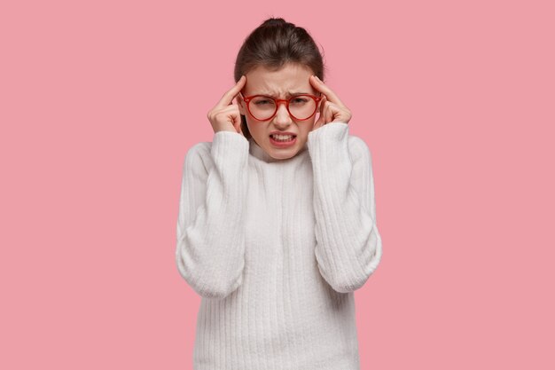 Young brunette woman wearing white sweater and red glasses