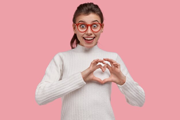 Young brunette woman wearing white sweater and red glasses
