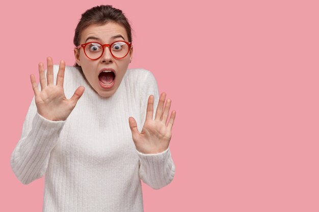 Free photo young brunette woman wearing white sweater and red glasses