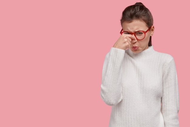 Young brunette woman wearing white sweater and red glasses