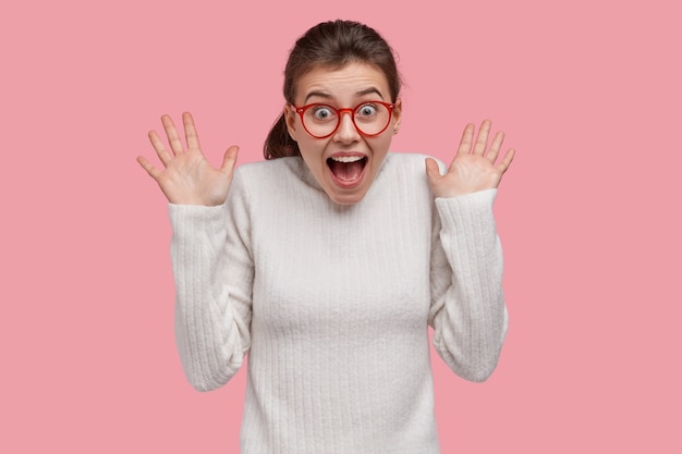 Young brunette woman wearing white sweater and red glasses