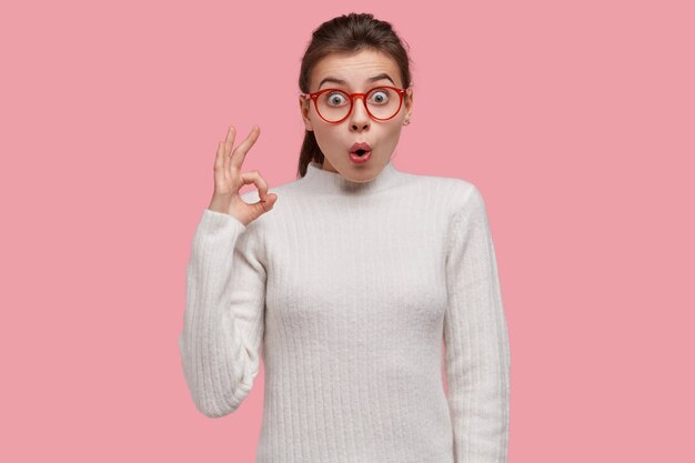 Young brunette woman wearing white sweater and red glasses