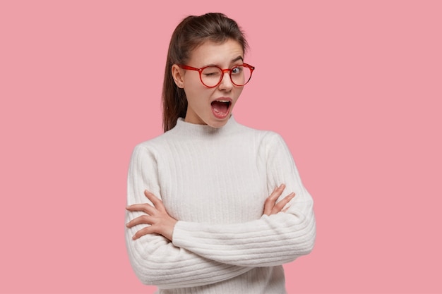 Young brunette woman wearing white sweater and red glasses