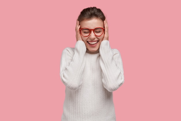 Young brunette woman wearing white sweater and red glasses