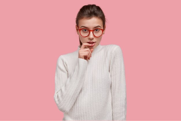하얀 스웨터와 빨간 안경에 젊은 갈색 머리 여자