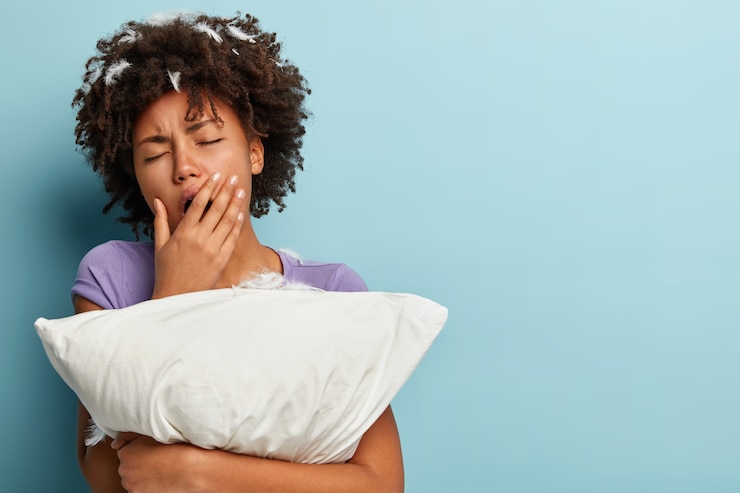 Free Photo young brunette woman with feathers in hair holding pillow