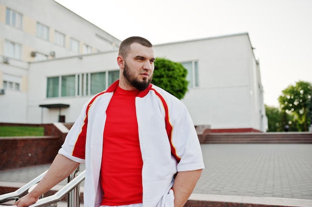 Young brutal bearded muscular man wear on white sport suit with red shirt