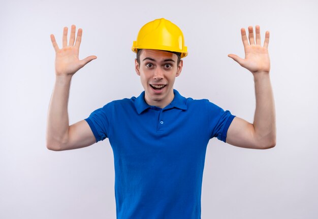 Young builder man wearing construction uniform and safety helmet doing happy arms up
