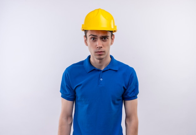 놀란 얼굴을하고 건설 유니폼과 안전 헬멧을 착용하는 젊은 작성기 남자