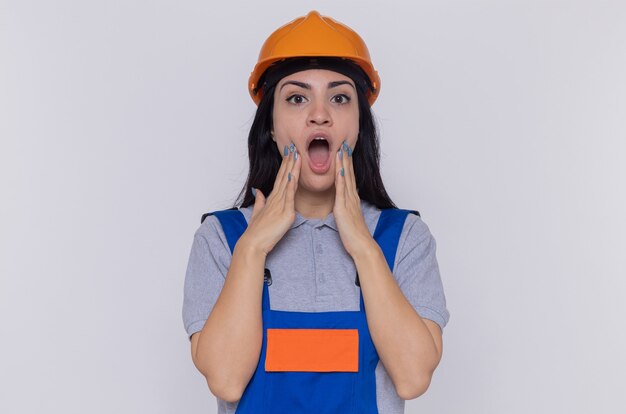 Young builder woman in construction uniform and safety helmet looking at camera