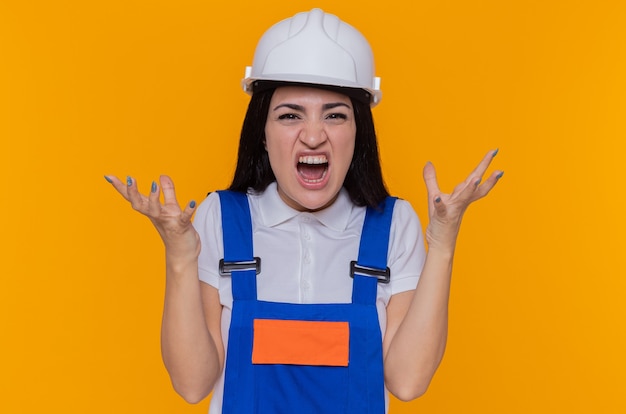 Молодой строитель женщина в строительной форме и защитный шлем кричит