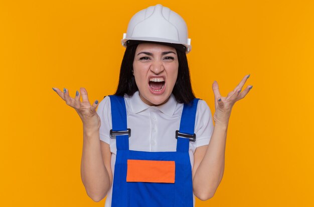 Young builder woman in construction uniform and safety helmet shouting
