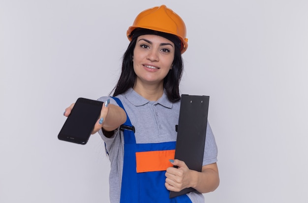 Молодая женщина-строитель в строительной форме и защитном шлеме