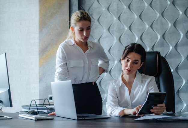 Young business lady female director sitting at office desk using calculator calculating working process business meeting working with colleague solving business tasks office collective concept