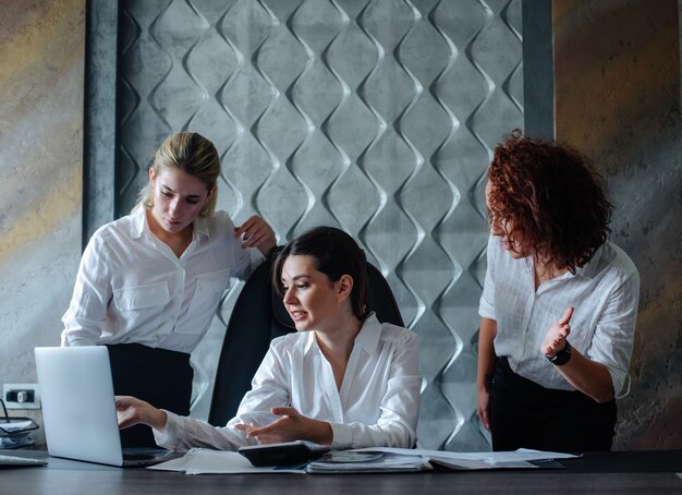 Young business lady female director sitting at office desk using laptop computer working process business meeting working with colleagues solving business tasks office collective concept