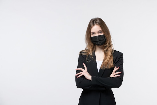 Young business lady in suit wearing surgical mask and listening someone carefully on isolated white wall