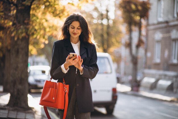 Young business lady using phone in the street