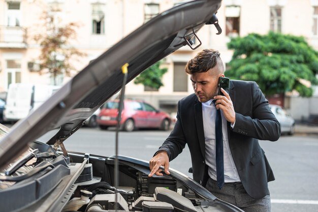 彼の車を修理しようとしている若いビジネスマン