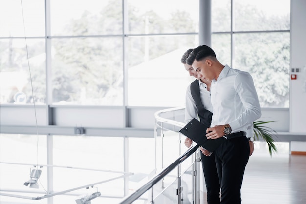 Free Photo young business people looking at documents and products standing at the office railing