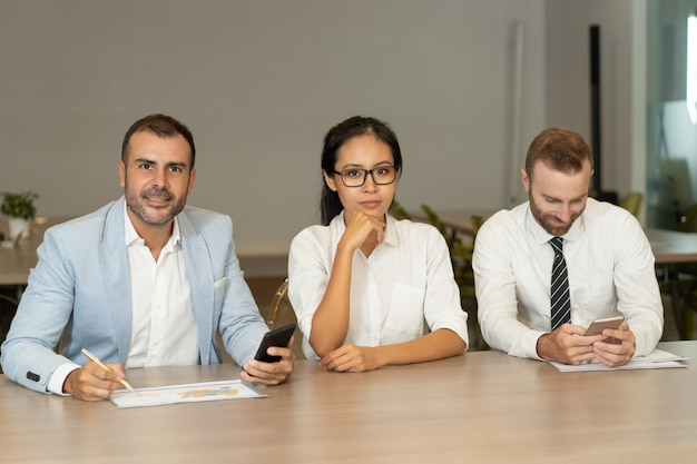 Young business people working and looking at camera at desk