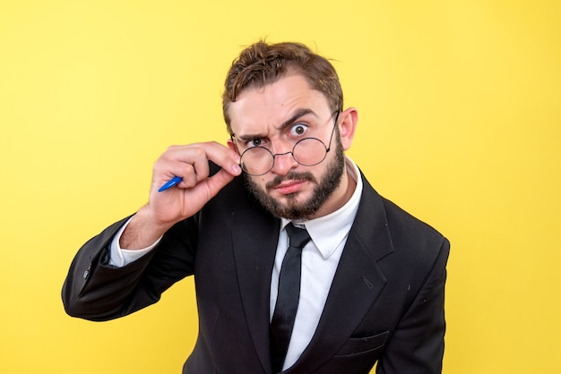 Young business person with glasses focused on one point over yellow