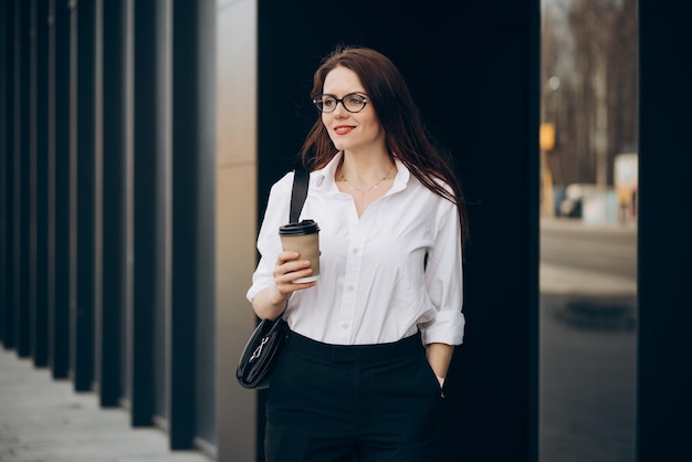 Young business woman drinking coffee by the business center