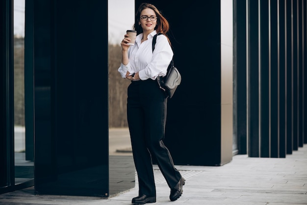 Free photo young business woman drinking coffee by the business center