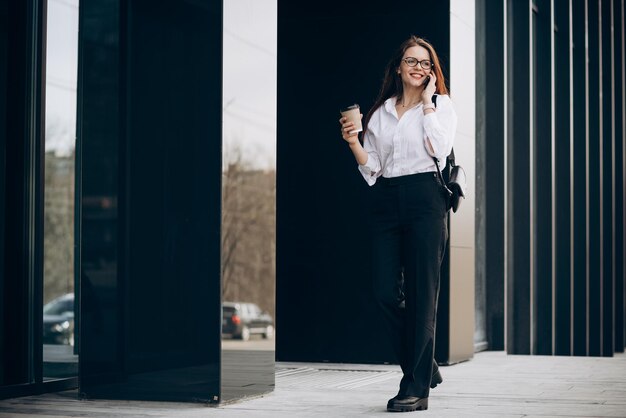 Young business woman drinking coffee by the business center