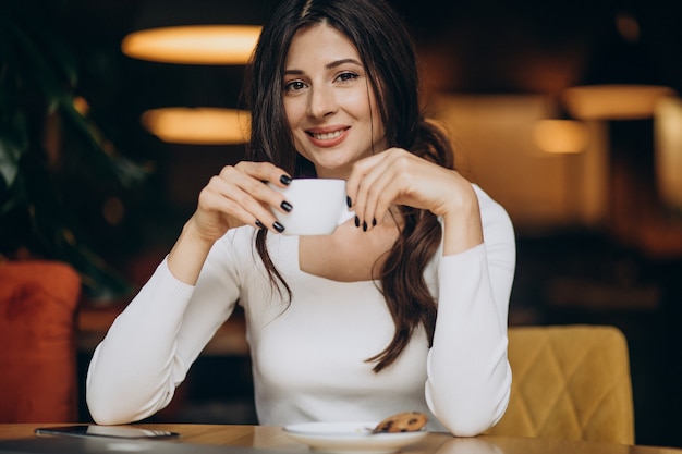 Free photo young business woman drinking coffee in a cafe