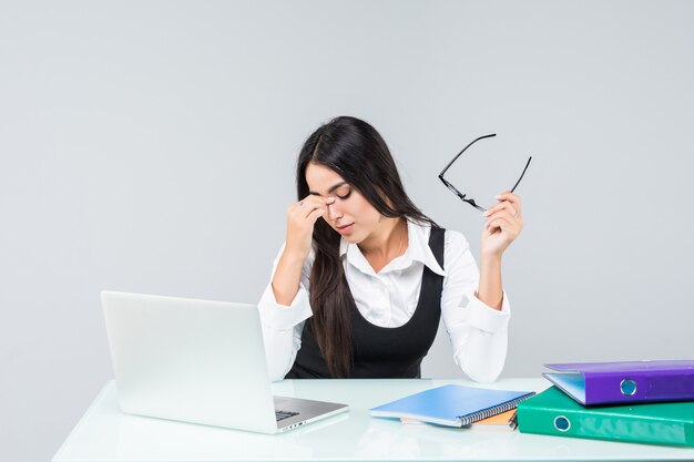 Young business woman feel tired and holding head at work desk isolated on white