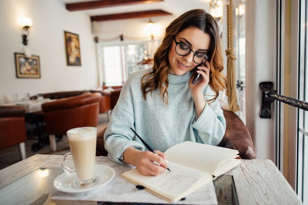 Young business woman in glasses leading business conversation on the phone 