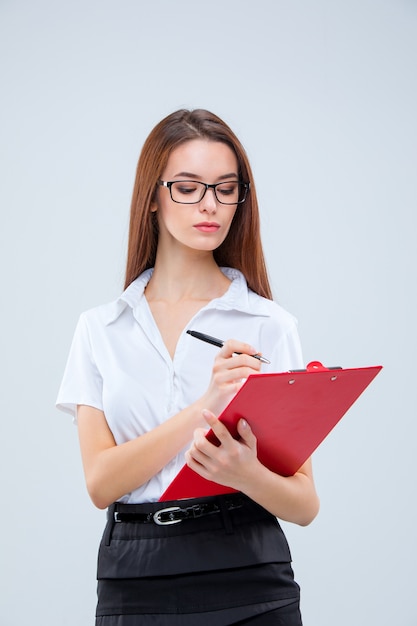 The young business woman in glasses with pen and tablet for notes on a gray