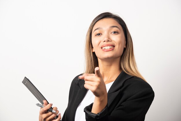 Young business woman holding clipboard and pointing