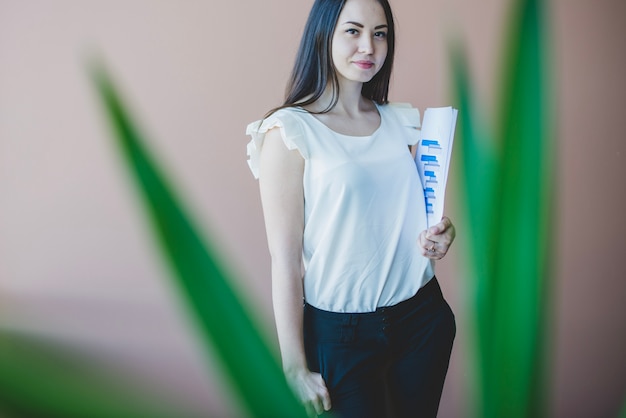 Young business woman behind plant