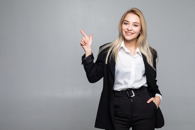 Young business woman pointing finger to the side on isolated grey wall