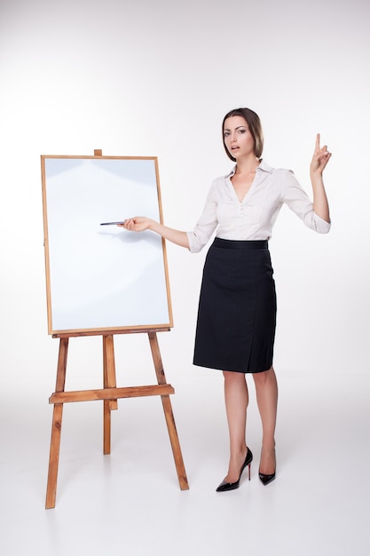 Young business woman showing something on the white wall