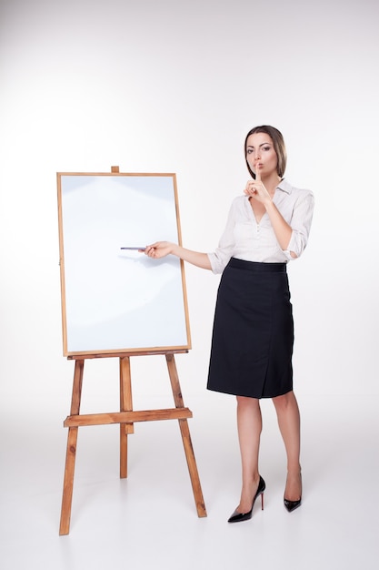 Free photo young business woman showing something on the white wall