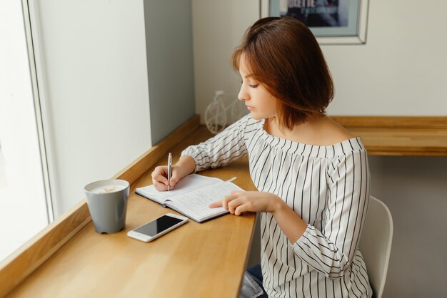 若い、ビジネス、女、テーブル、カフェ、スマートフォン、ノートブック、仕事