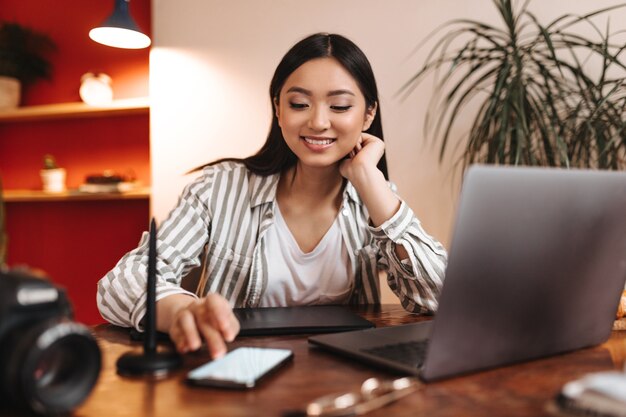 Young business woman smiles and looks into phone screen