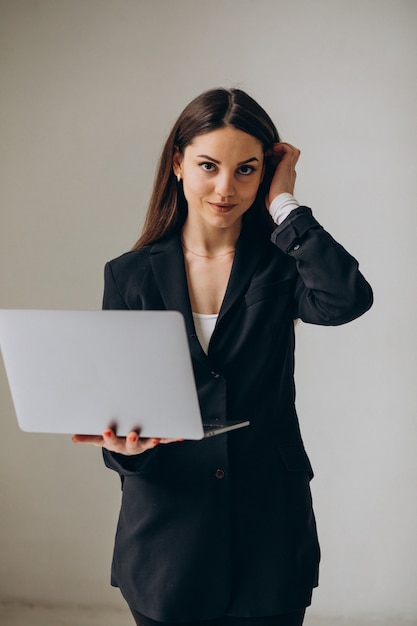 オフィスでラップトップを持って立っている若いビジネス女性