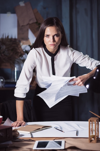 Young business woman throwing documents. Disappointed and annoyed by unsuccessful project.