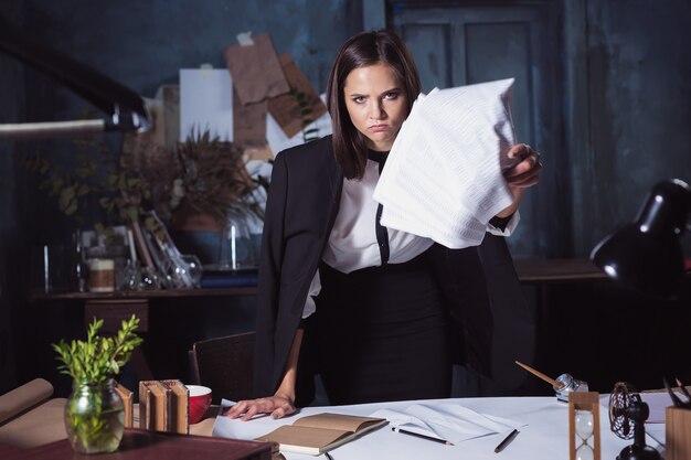 Young business woman throwing documents . Disappointed and annoyed by unsuccessful project.